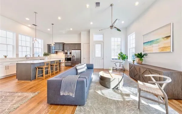 a living room with stainless steel appliances kitchen island granite countertop furniture and a wooden floor