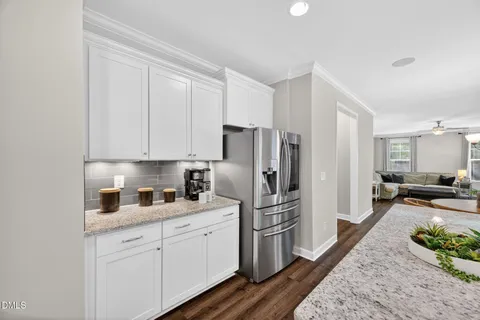 a kitchen with stainless steel appliances granite countertop a refrigerator a sink dishwasher a stove and white countertops with wooden floor