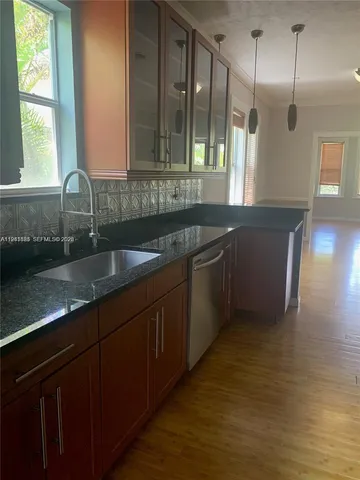 a kitchen with stainless steel appliances granite countertop a sink a counter space and a window