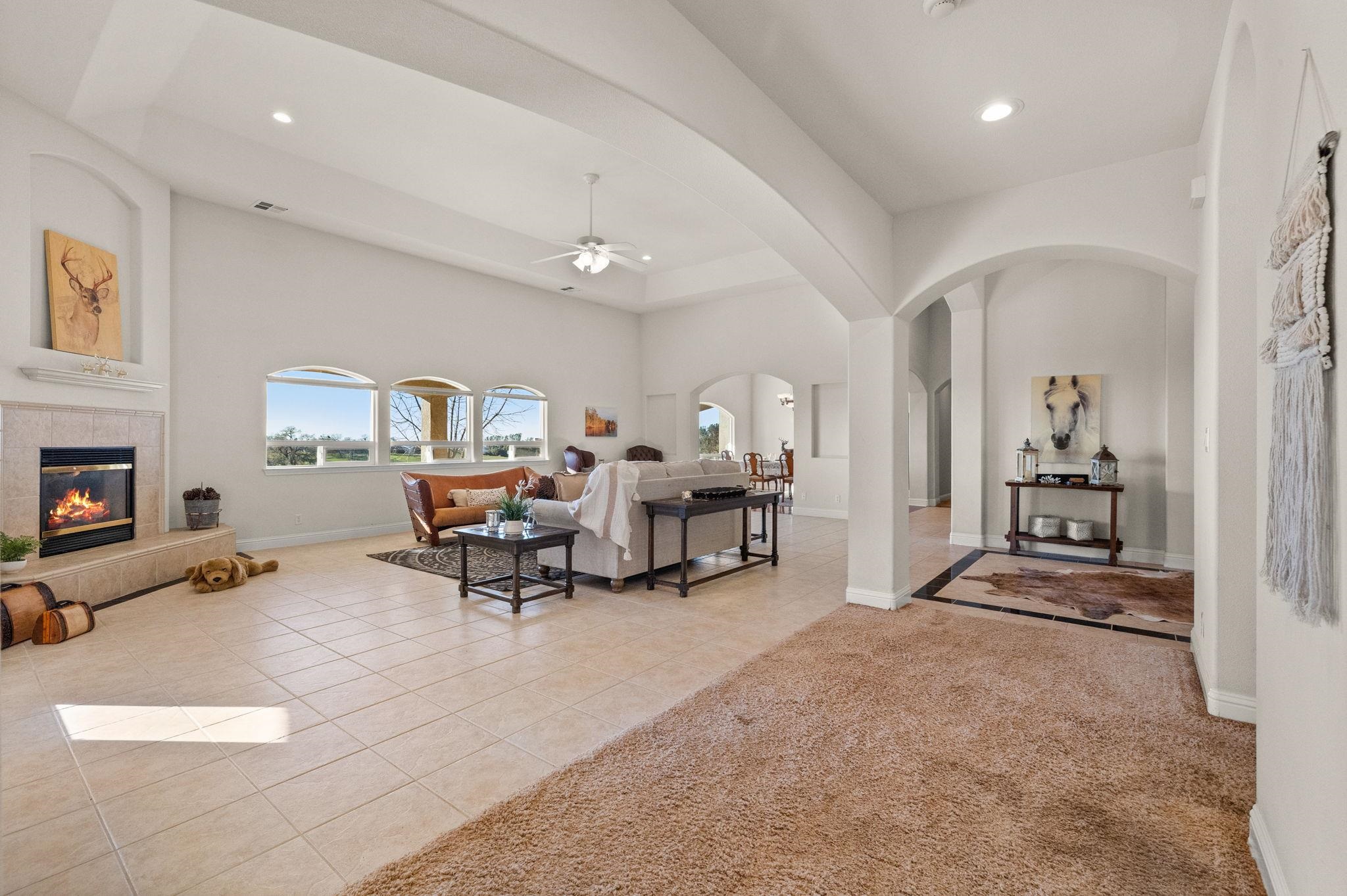 17550 Old Wards Ferry Road Sonora, CA 95370 - Photo 13 of 59 Living area featuring light tile patterned floors, ceiling fan, light colored carpet, a fireplace, and arched walkways