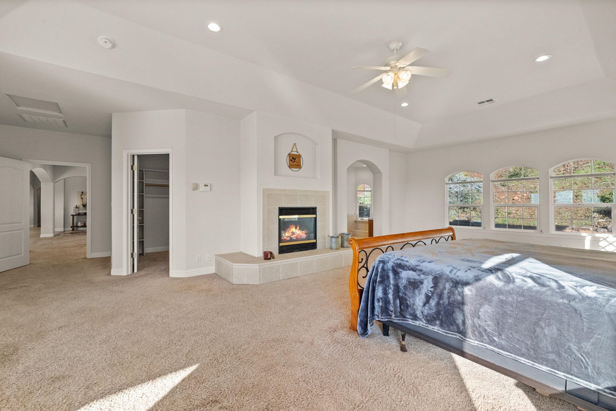17550 Old Wards Ferry Road Sonora, CA 95370 - Photo 20 of 59 Carpeted bedroom featuring arched walkways, a walk in closet, a fireplace, ceiling fan, and recessed lighting