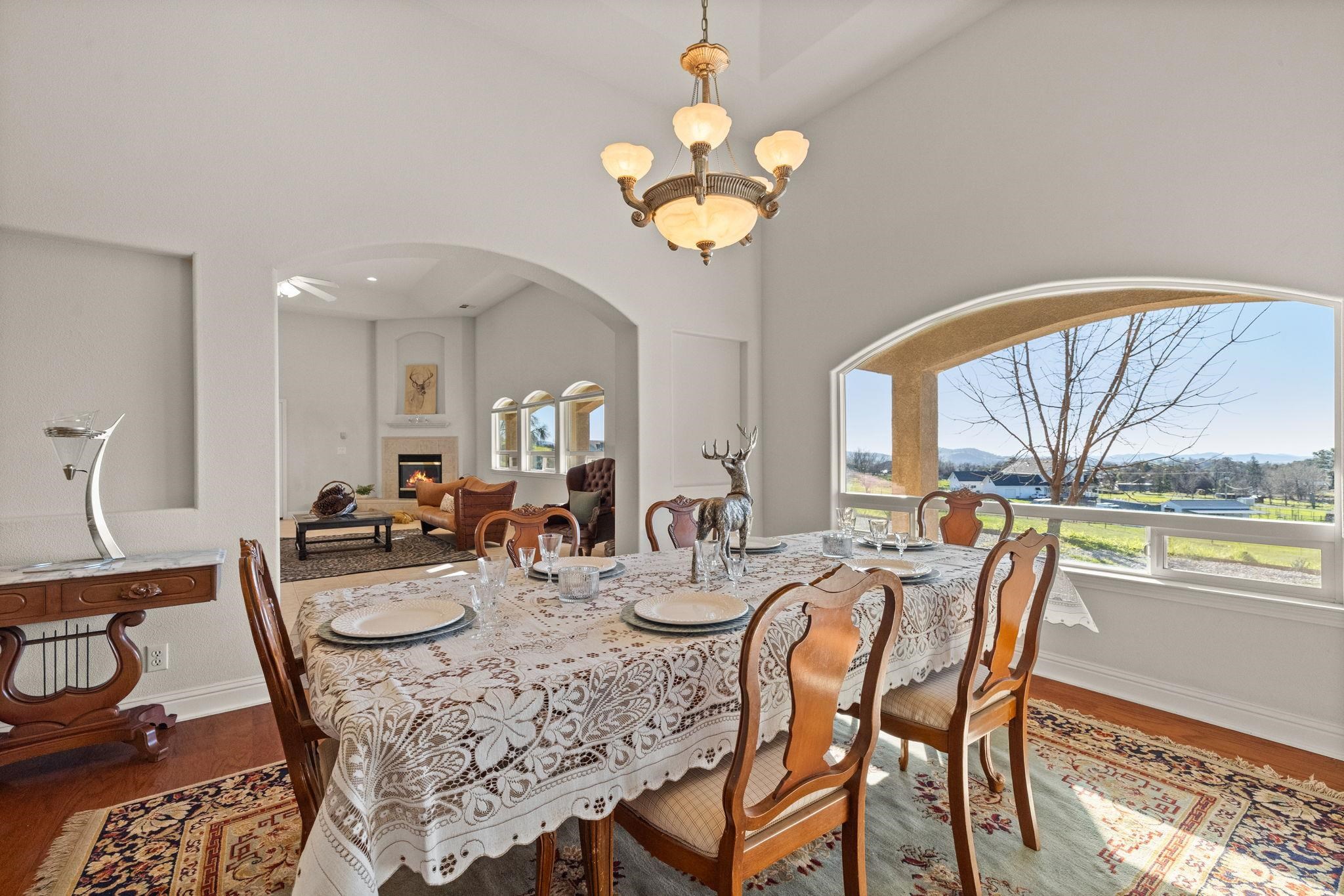 17550 Old Wards Ferry Road Sonora, CA 95370 - Photo 26 of 59 Dining area with a chandelier, a glass covered fireplace, wood finished floors, and arched walkways