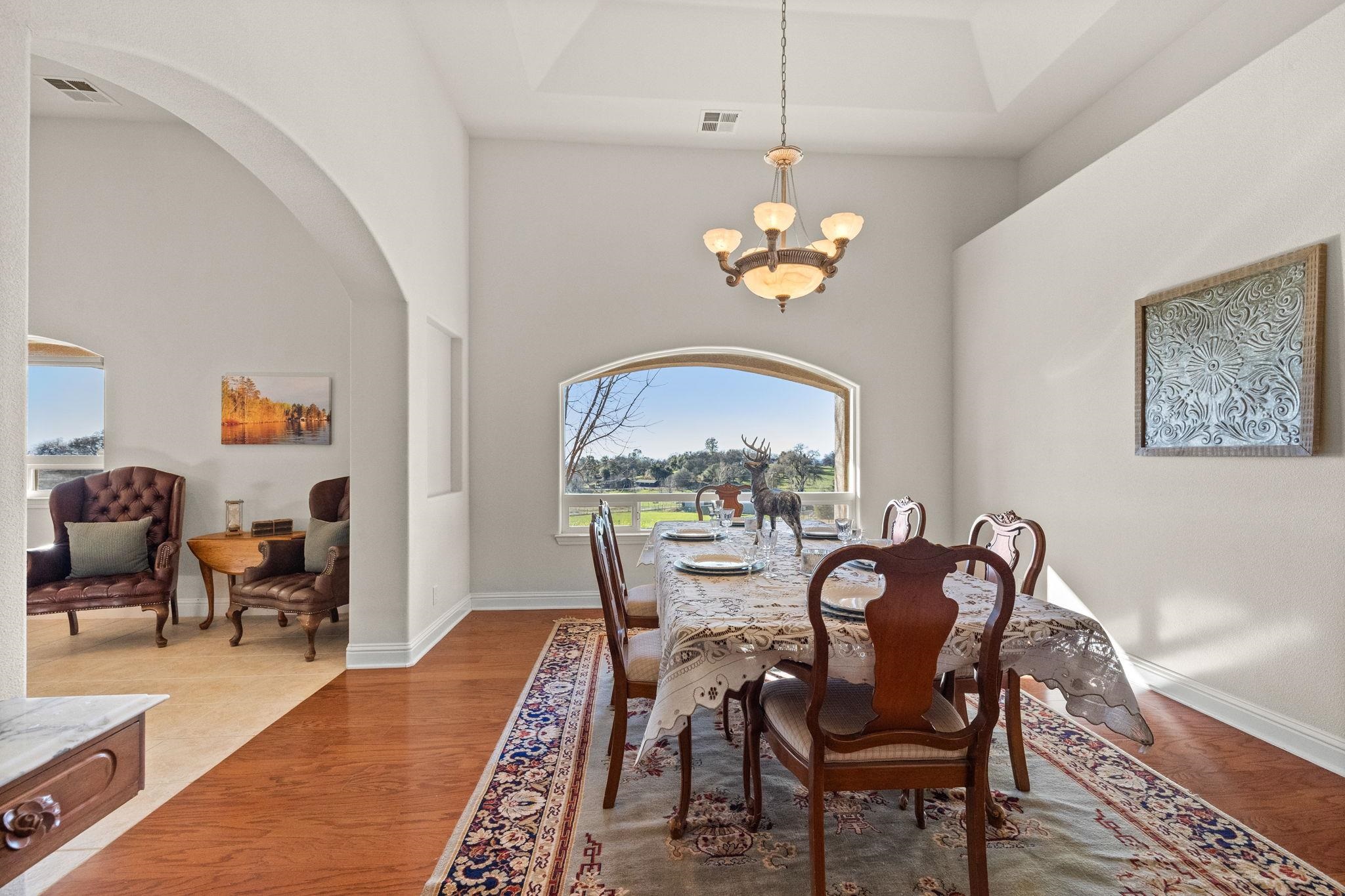 17550 Old Wards Ferry Road Sonora, CA 95370 - Photo 27 of 59 Dining area featuring a high ceiling, arched walkways, a chandelier, wood finished floors, and a tray ceiling