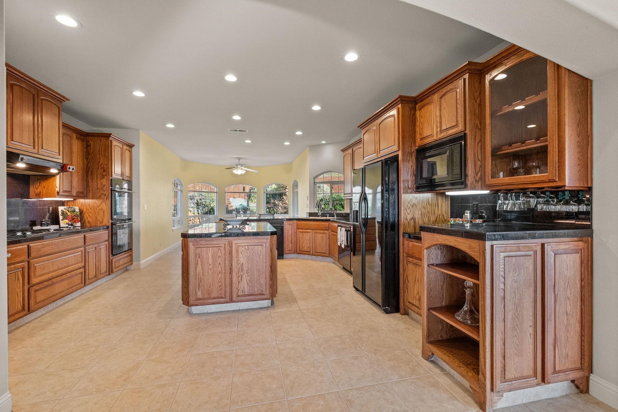 17550 Old Wards Ferry Road Sonora, CA 95370 - Photo 28 of 59 Kitchen with tasteful backsplash, recessed lighting, brown cabinets, a kitchen island, and black appliances