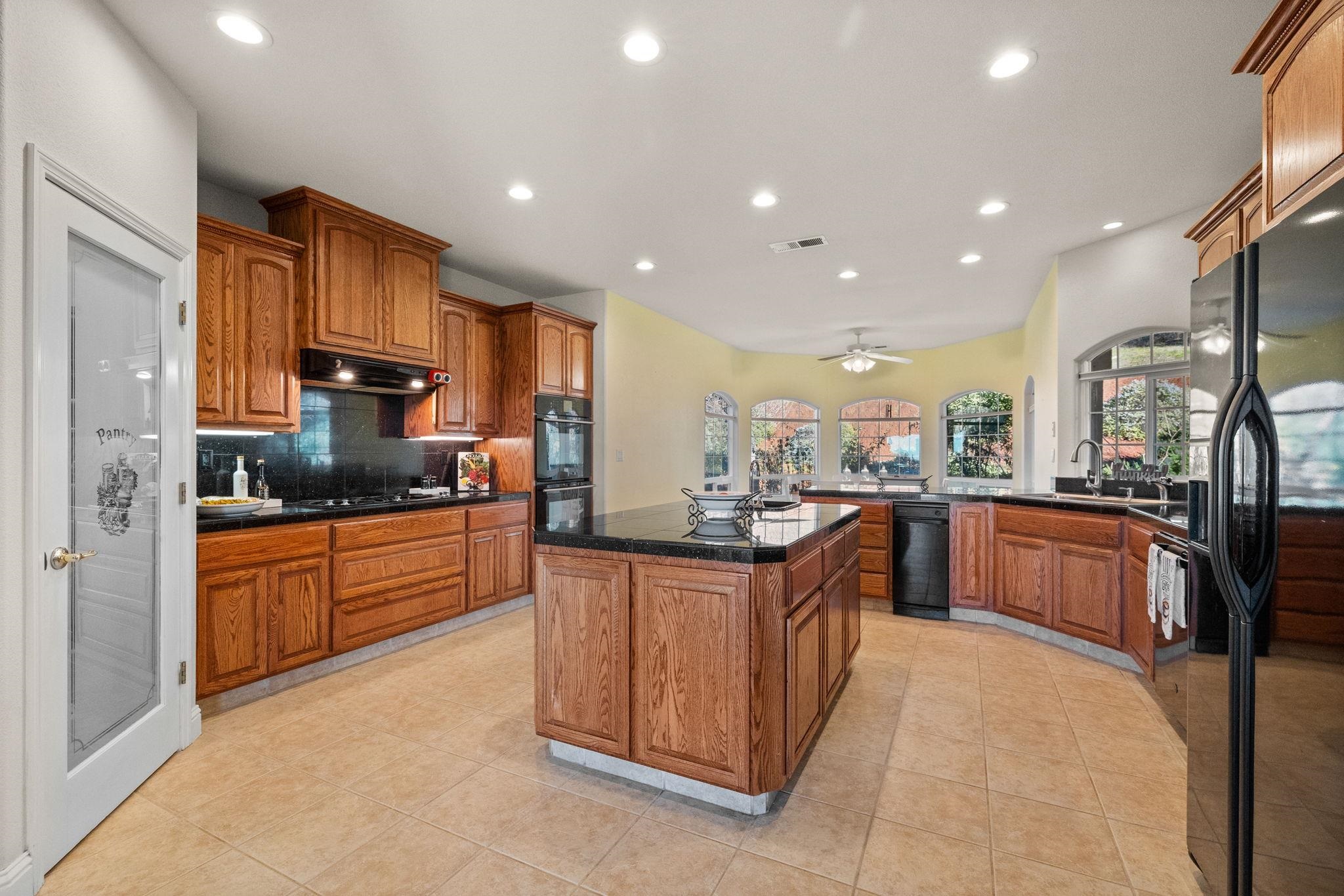 17550 Old Wards Ferry Road Sonora, CA 95370 - Photo 30 of 59 Kitchen featuring dark countertops, brown cabinets, black appliances, recessed lighting, and decorative backsplash