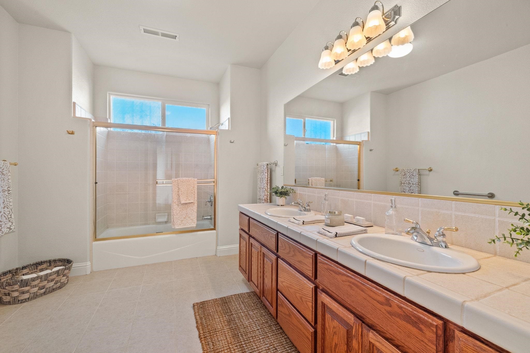 17550 Old Wards Ferry Road Sonora, CA 95370 - Photo 38 of 59 Bathroom featuring double vanity, bath / shower combo with glass door, light tile patterned flooring, and backsplash
