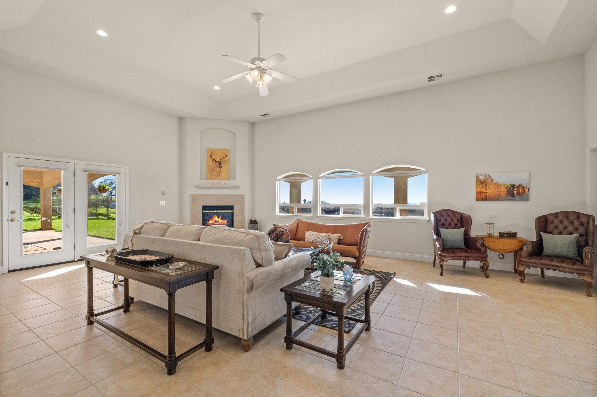 17550 Old Wards Ferry Road Sonora, CA 95370 - Photo 9 of 59 Living room with a high ceiling, a tile fireplace, recessed lighting, a tray ceiling, and light tile patterned floors