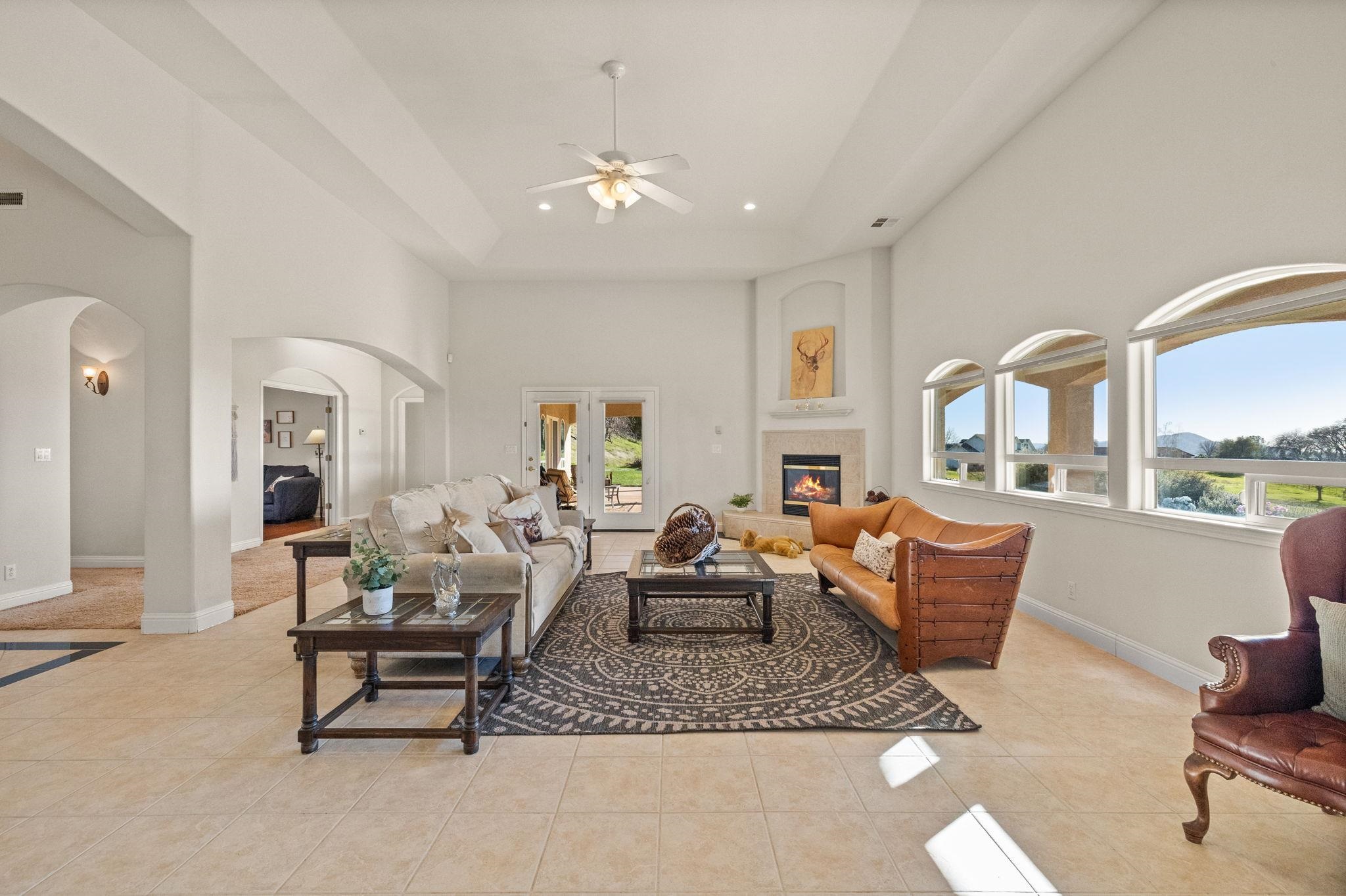 17550 Old Wards Ferry Road Sonora, CA 95370 - Photo 10 of 59 Living area with a towering ceiling, arched walkways, a fireplace, light tile patterned floors, and ceiling fan