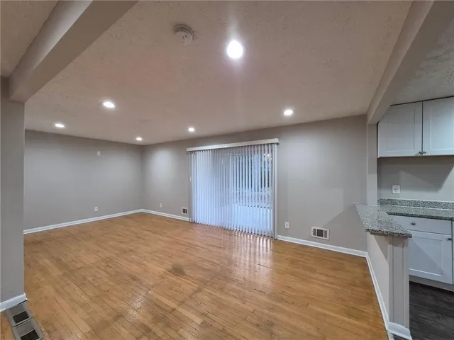 a view of an empty room with wooden floor and a fireplace