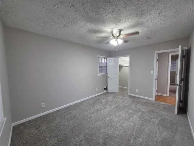 an empty room with chandelier fan and closet area