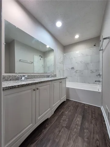 a spacious bathroom with a granite countertop sink a mirror and a bathtub