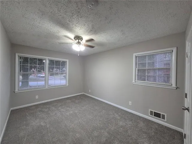 an empty room with windows and chandelier fan