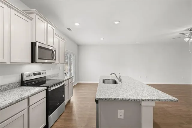 a kitchen with granite countertop kitchen island stainless steel appliances a sink stove top oven and microwave