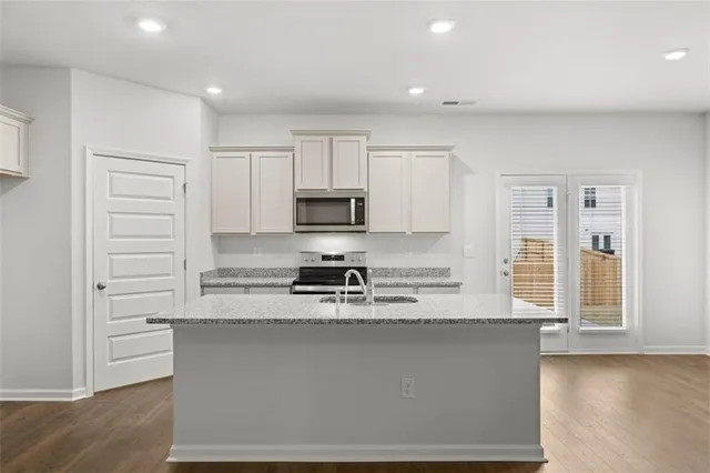 a large kitchen with stainless steel appliances granite countertop a stove a sink and a refrigerator
