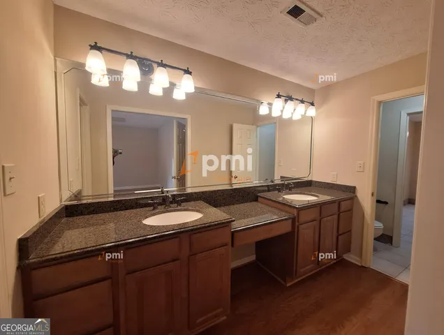 a bathroom with a granite countertop sink a light fixture and a mirror