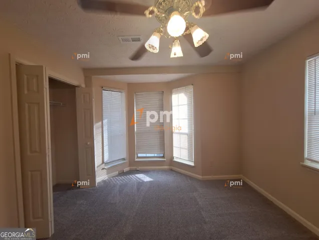 an empty room with a chandelier fan and windows