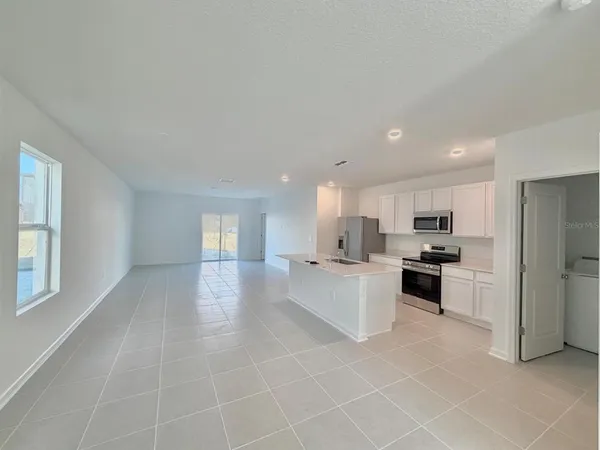 a large white kitchen with a sink and dishwasher a stove top oven with wooden floor