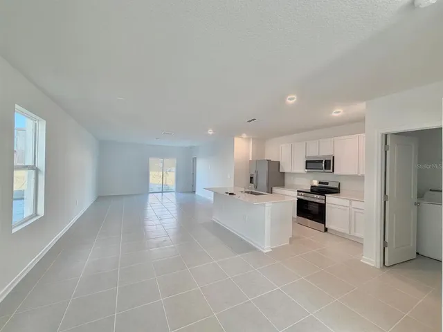 a large white kitchen with a sink and dishwasher a stove top oven with wooden floor