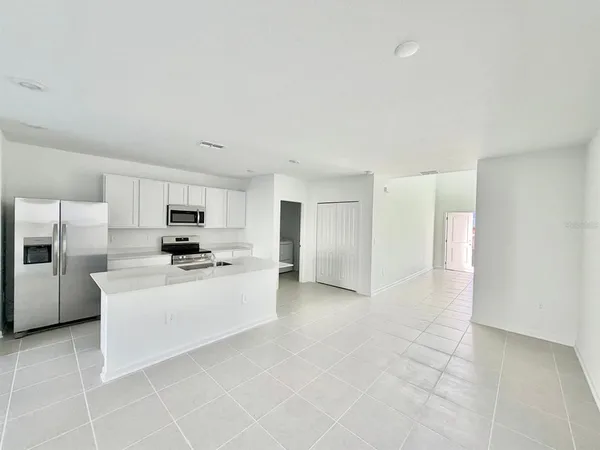 a large white kitchen with cabinets a sink a window and a refrigerator
