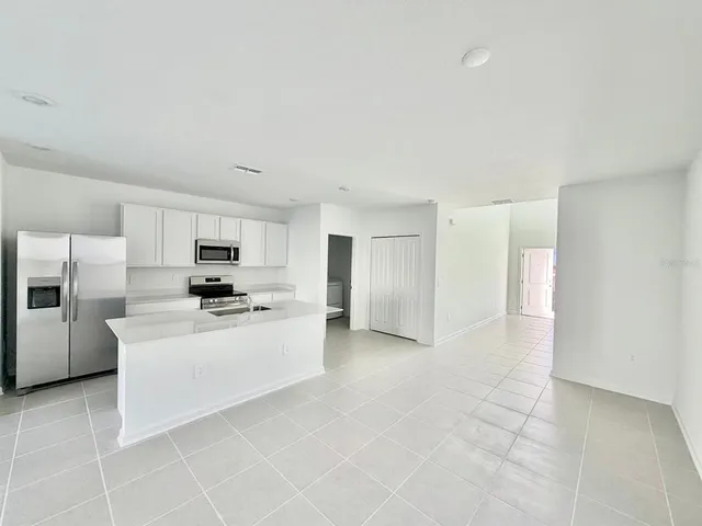 a large white kitchen with cabinets a sink a window and a refrigerator