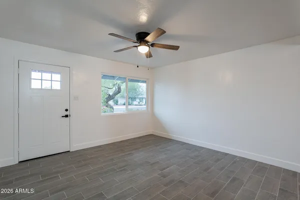a view of an empty room with wooden floor and a ceiling fan