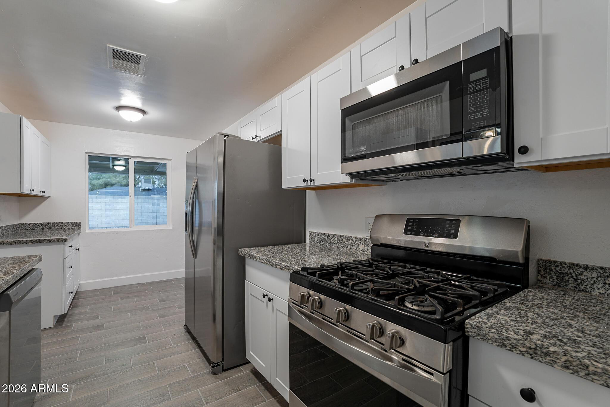 536 West 18th Street Tempe, AZ 85281 - Photo 24 of 39 a kitchen with stainless steel appliances kitchen island granite countertop wooden cabinets and a stove top oven
