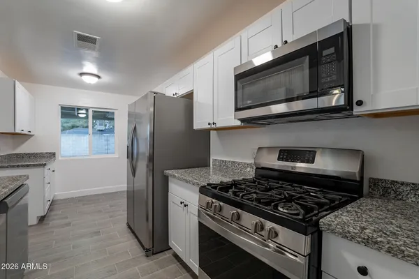a kitchen with granite countertop a sink stove and refrigerator