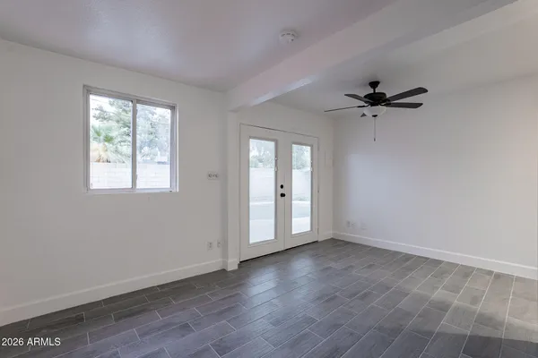 an empty room with wooden floor and a ceiling fan