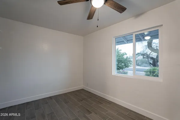 a view of an empty room with a window and wooden floor