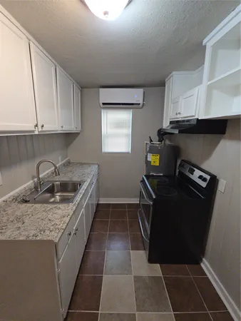 a kitchen with granite countertop a stove a sink and a refrigerator