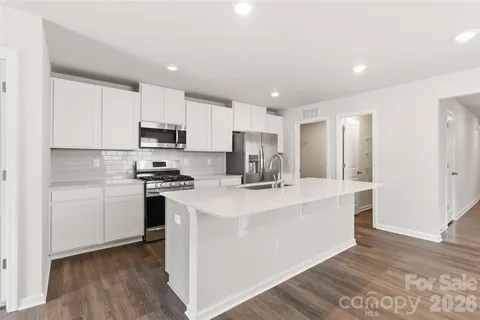 a kitchen with kitchen island a white counter top space a stove and cabinets
