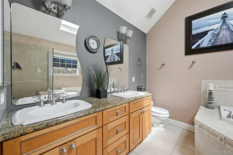 a bathroom with a granite countertop toilet sink and mirror