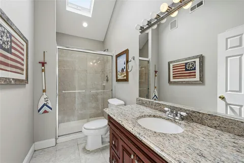 a bathroom with a granite countertop double vanity sink toilet and shower