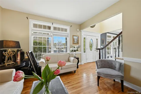 a living room with furniture hard wood floor and a floor to ceiling window