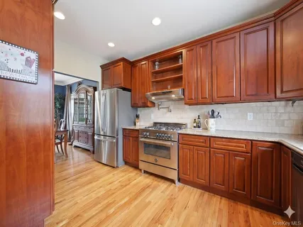 a kitchen with stainless steel appliances granite countertop a refrigerator a sink dishwasher and wooden cabinets with wooden floor