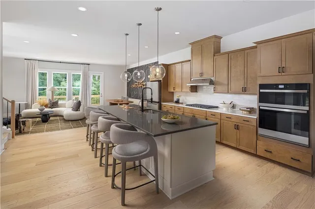 a kitchen with stainless steel appliances granite countertop a stove top oven a sink dishwasher a dining table and chairs with wooden floor