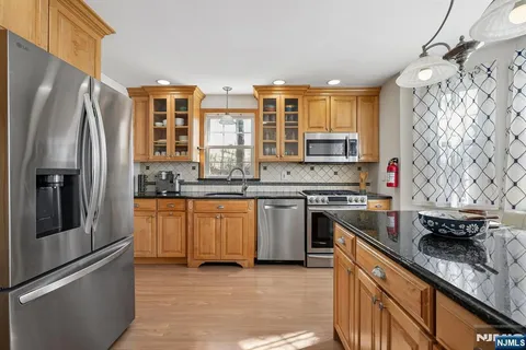 a kitchen with stainless steel appliances granite countertop a refrigerator a stove and a sink