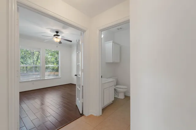 an empty room with wooden floor chandelier fan and windows