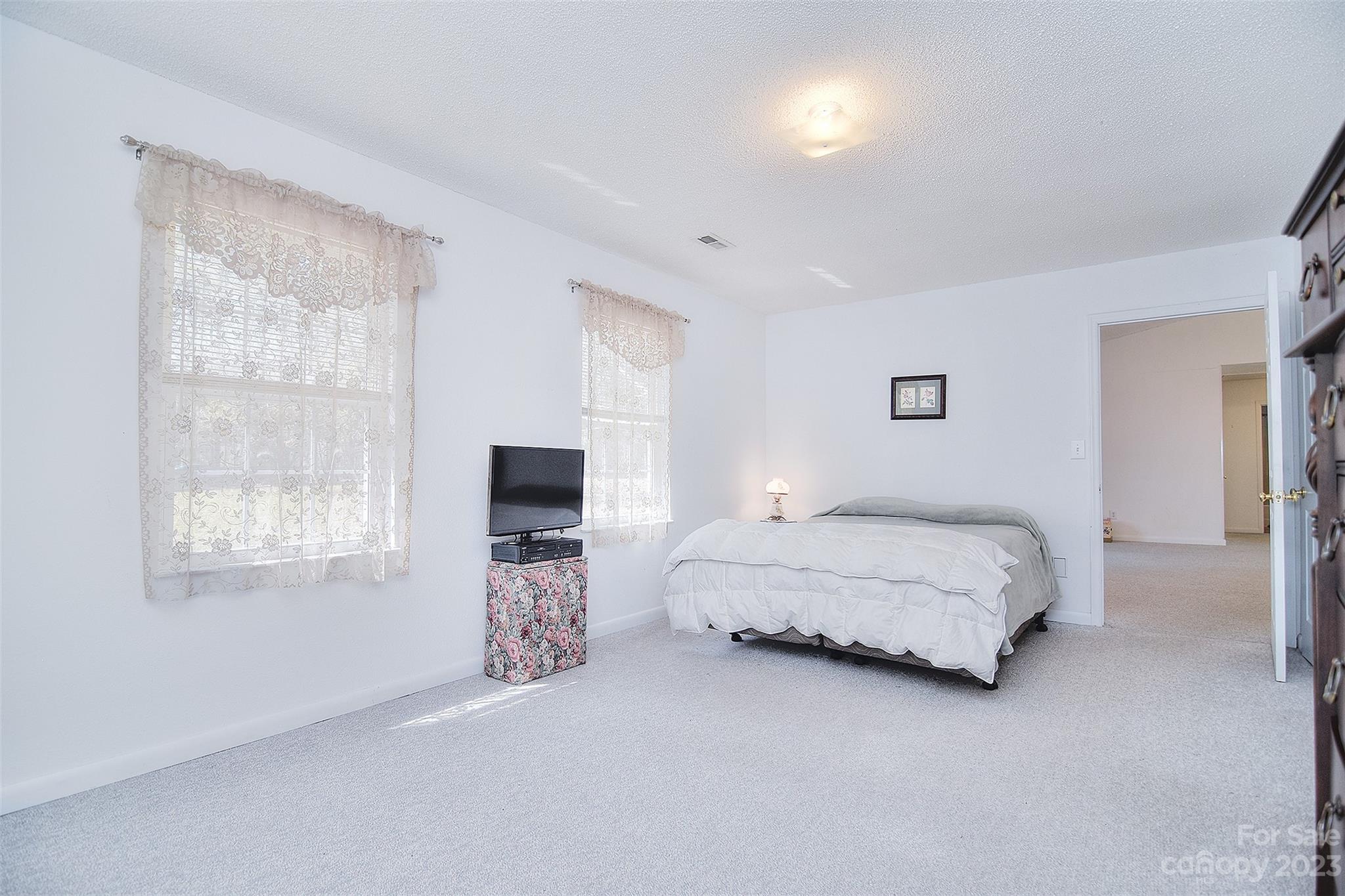 8705 Simpson Road Waxhaw, NC 28173 - Photo 23 of 46 a spacious bedroom with a bed and a tv on the dresser