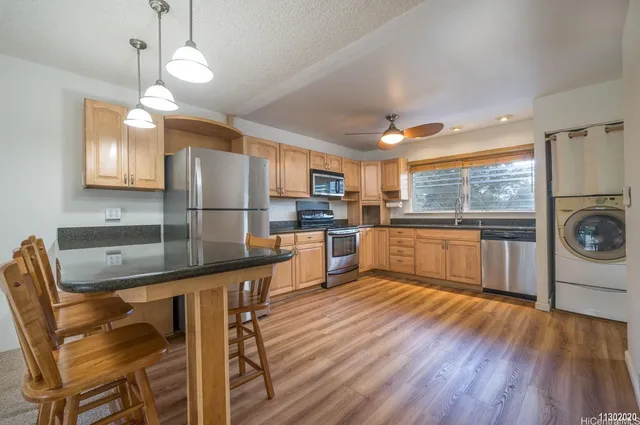 a kitchen with stainless steel appliances granite countertop a refrigerator a stove top oven a sink dishwasher and white cabinets with wooden floor