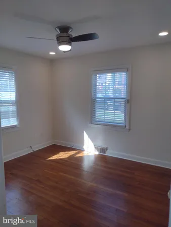an empty room with wooden floor chandelier fan and windows