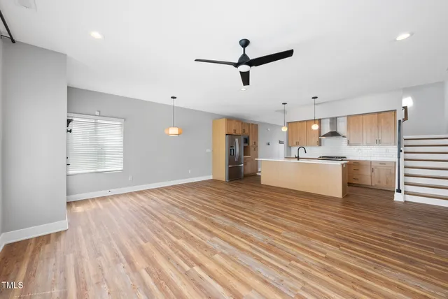 a view of a kitchen with kitchen island a sink wooden floor and appliances