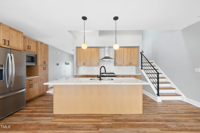 a view of a kitchen with kitchen island a sink wooden floor and living room view