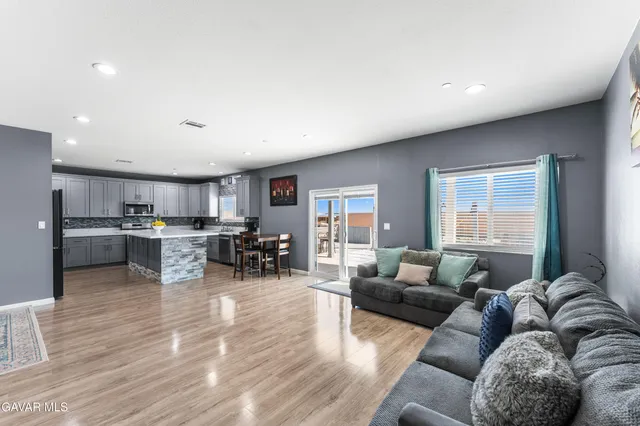 a living room with furniture and kitchen view with wooden floor