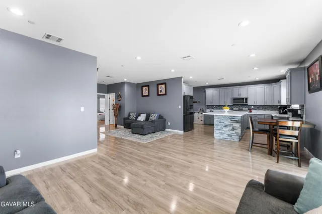 a kitchen with stainless steel appliances kitchen island granite countertop a refrigerator and couches