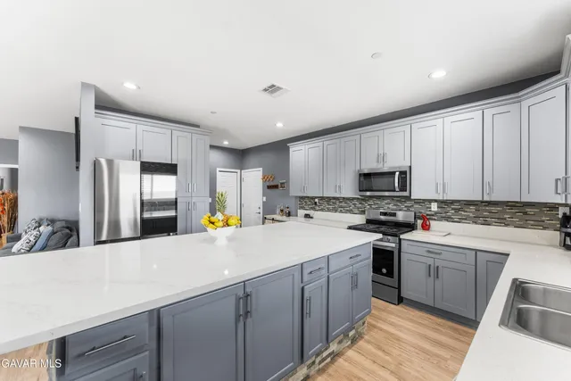 a kitchen with stainless steel appliances a stove refrigerator sink and wooden cabinets