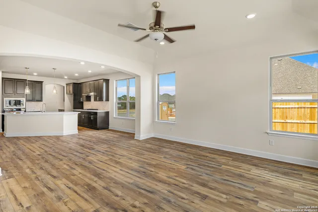 a view of a kitchen with a stove cabinets a ceiling fan and wooden floor