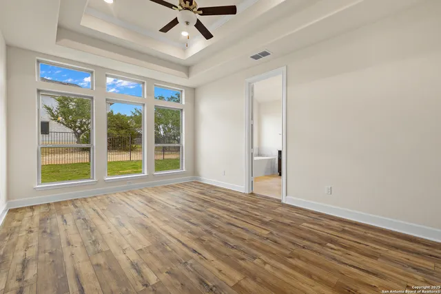 a view of an empty room with a window and wooden floor