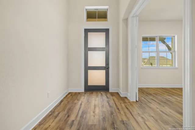 an empty room with wooden floor and windows