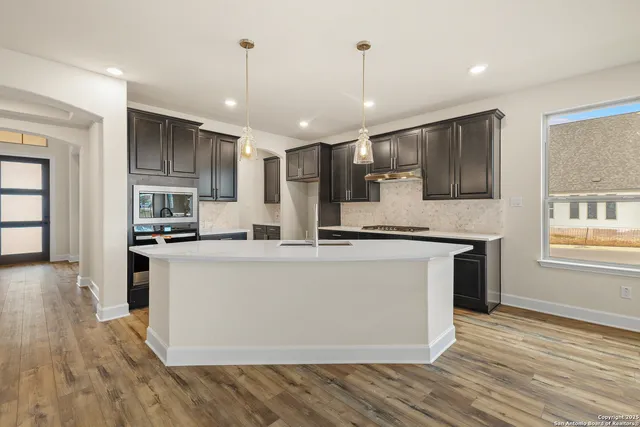 a large kitchen with stainless steel appliances granite countertop a refrigerator a stove a sink dishwasher and a oven with wooden floor